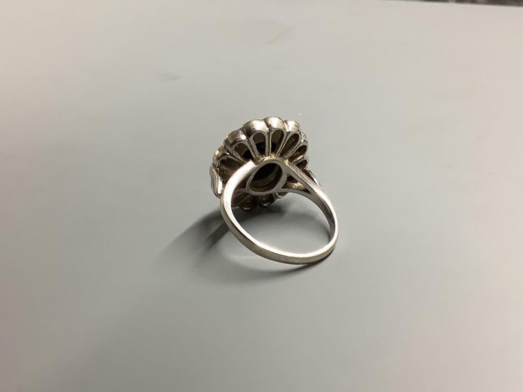 A modern 18ct white gold, sapphire and diamond set oval cluster ring, size L/M, gross weight 7.5 grams.